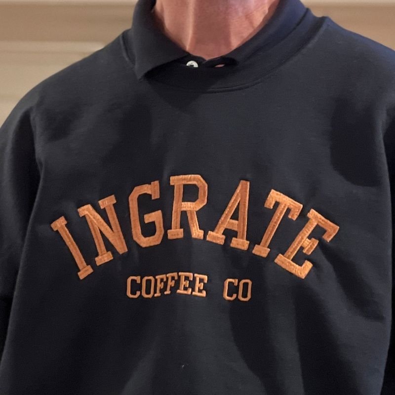 Customer photo: navy sweatshirt with orange arched INGRATE Coffee Co embroidery