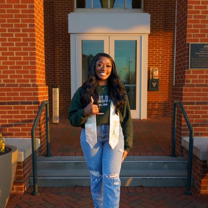 Customer photo: graduate wearing a green embroidered sweatshirt and stole for college graduation pictures