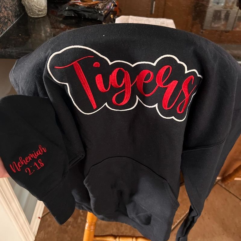 Customer photo: black hoodie with red Tigers script embroidery and a matching beanie