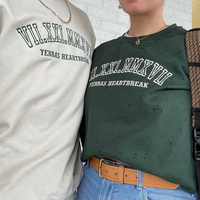 Customer photo: couple in cream and forest green sweatshirts with Roman numeral date embroidery